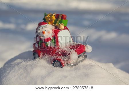 Cheerful Toy Snowman On A Car Carries Gifts. New Year