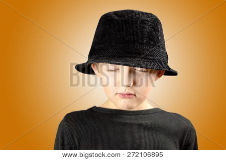 Closeup Of Young Boy In Black Shirt And Black Hat With Very Calm, Meditating And Focused Expression 