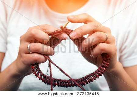 Close-up Of A Dark-haired Beautiful Woman Smiling And Knitting With Knitting Crochet From A Natural 