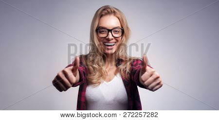 Studio Portrait Of Pretty Blond Hipster Woman Wearing Glasses And Red Plaid Shirt Gesturing Thumbs U