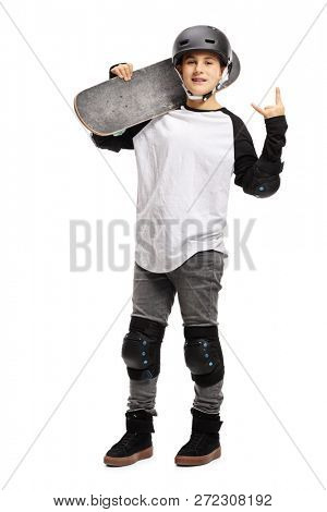 Full length portrait of a young boy posing with a skateboard and gesturing rock and roll isolated on white background