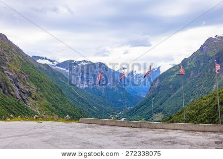Norwegian Flags Waving Against Mountains Landscape. Travel, Holidays And Adventure Concept.