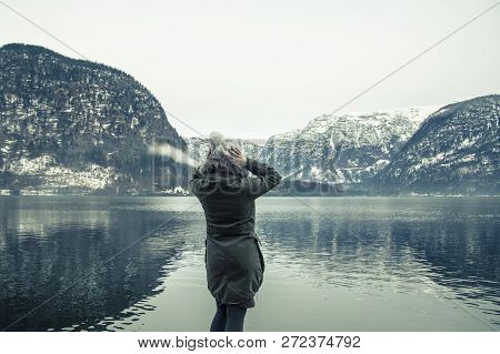 Woman Traveler On The Background Of Halstatter See In Winter. Alps, Austria. Winter Mountains Landsc