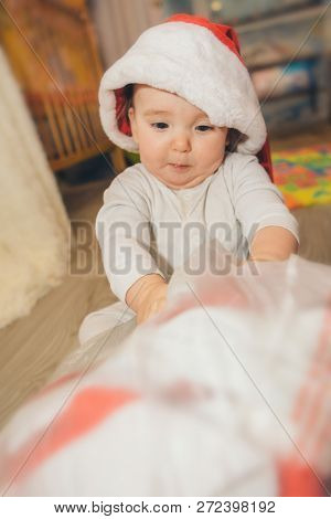A Naked Baby Plays In A Christmas Hat.