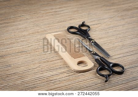 Scissors And A Hairbrush On A Light Wooden Tabletop