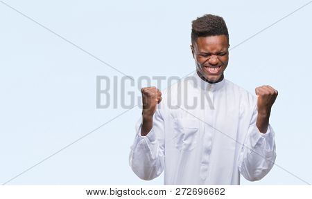 Young arabic african man wearing traditional djellaba over isolated background very happy and excited doing winner gesture with arms raised, smiling and screaming for success. Celebration concept.