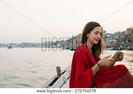 Western woman on a boat texting from the River Ganges
