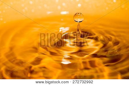 A Drop Of Liquid Bouncing Back With Golden Reflections