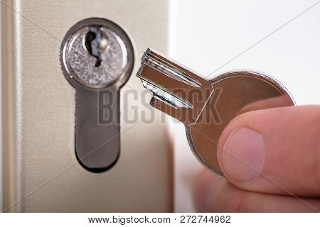 Close-up Of A Man Holding Broken Key Near Keyhole