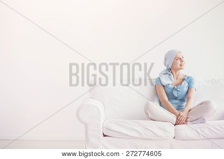 Happy Teenage Girl Suffering From Breast Cancer, Wearing Blue Headscarf And Siting Cross Leg On The