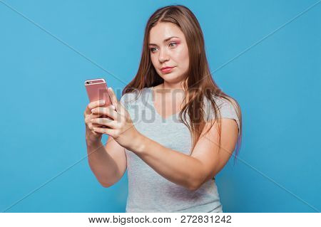 Young Attractive Caucasian Woman With Brown Hair And Bright Blue Eyes Looks To The Pink Mobile Phone