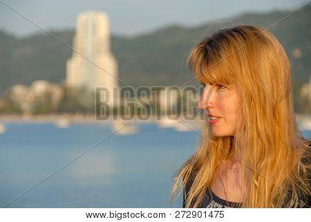 Face And Shoulders Portrait Of Caucasian Female With Long Yellow To Orange Hair Looking Left. In The