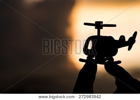 Helicopter Model On Hands Of Silhouette In Sunligt Sky. Travel And Air Travel Fast And Secure Travel