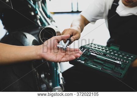 Young Professional Technican Maintanance Motorcycle With Team At The Service Shop.