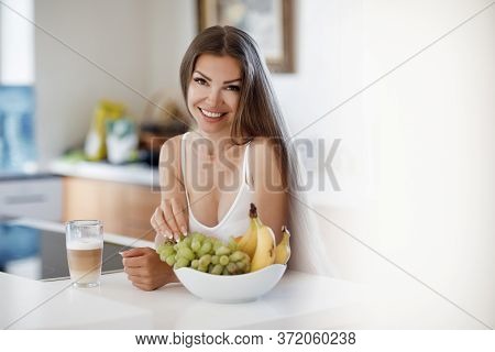 Portrait Of A Young Smiling Woman At Home With Fruits And Coffee