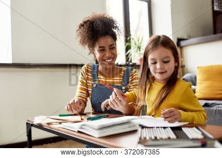 Caucasian Little Girl Spending Time With African American Baby Sitter. They Are Drawing, Learning To