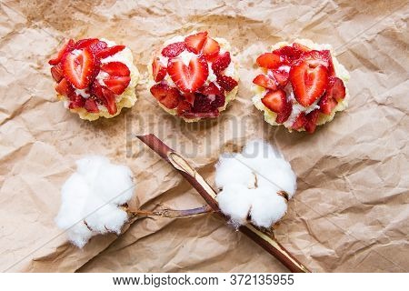 Beautiful Cupcakes With Strawberries Along With A Branch Of Cotton Lies On Kraft Paper.