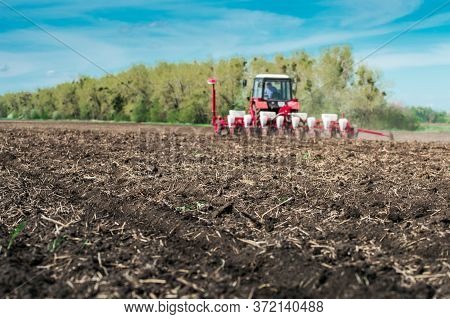 Tractor With Planter In The Field On A Sunny Day