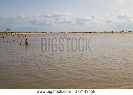 Arabat Spit, Ukraine - August 23, 2017: Unknown People Bathe In The Salt Lake. Composition Of The Wa