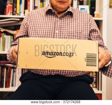 Paris, France - April 2, 2019: Happy Senior Man Holding In Living Room New Delivered Parcel From Ama