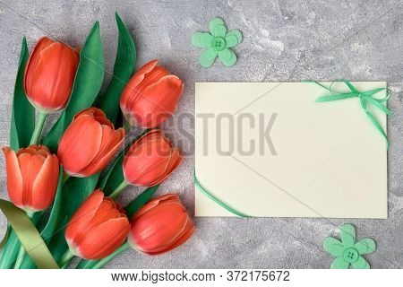Spring Greetings, Flat Lay With Red Tulips And Blank Paper Card On Grey Textured Background. Easter,