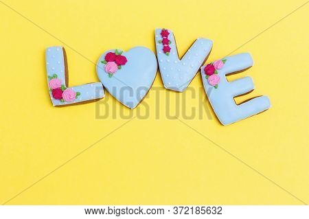 Inscription Love By Homemade Cookies With Blue Icing On Yellow Pastel Color. Love Romance Concept. V