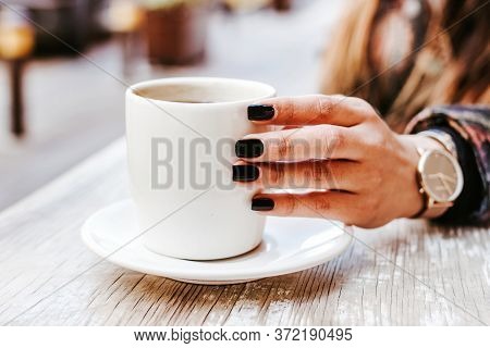 Woman Hand Holding A Cup Of Coffee Outdoors At Coffee Shop Or Cafe With Blurred Background