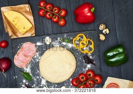 Pizza Dough With Ingredients On A Dark Background.