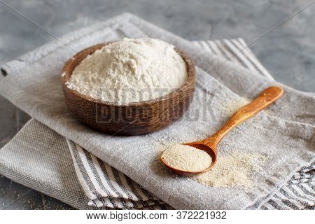 Bowl Of Raw Fonio Flour And A Spoon Of Fonio Seeds On Napkin Close Up. Alternative Flour