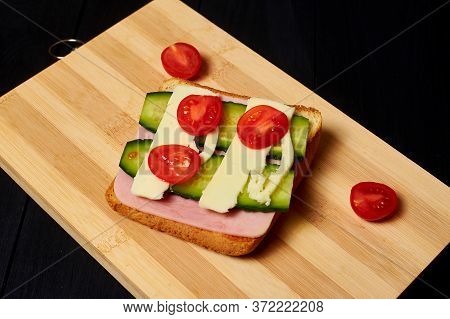 Toast With Ham, Cheese, Cucumber And Tomato On A Light Wooden Board.