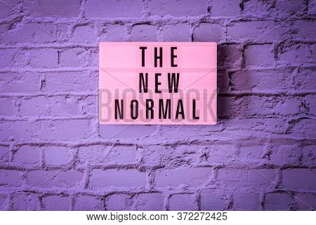 The New Normal Sign Hanging On Wall In Neon Colors. Pink Signboard The New Normal In On Vintage Purp