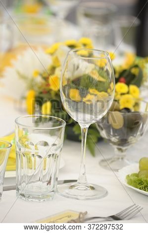 Wine Glass And Glass And Yellow Flowers On The Table, Table Setting