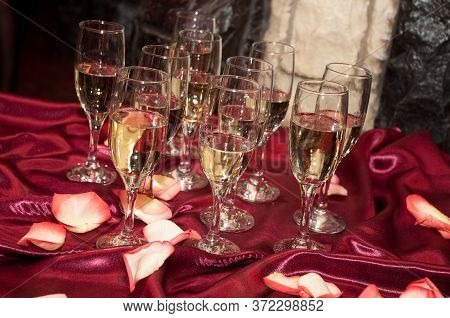 Glasses With Champagne On A Red Tablecloth With Rose Petals
