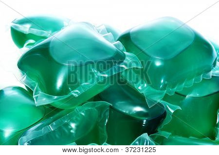 un mucchio di bustine detersivo bucato liquido su uno sfondo bianco