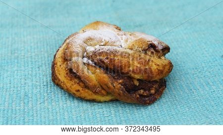Close-up View Of Sweet Cinnamon Roll On The Blurred Turquoise Background. Danish Pastry. Sweet Pastr
