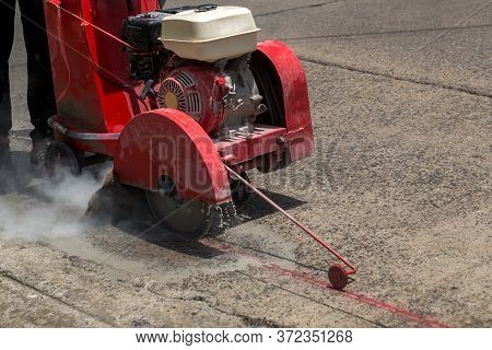 Concrete Road Cutters With Worker. Worker Using Diamond Saw Blade Machine Cutting Concrete Road At C
