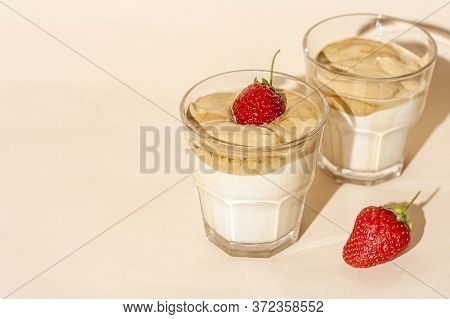 Dalgon Coffee In A Transparent Glass With Milk On A Pastel Background With Strawberries.