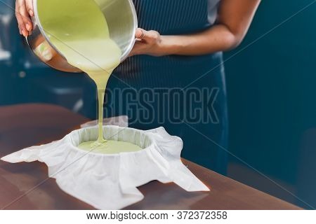 Woman Pouring Matcha Green Tea Dough Into A Mold Padded With Parchment Paper.