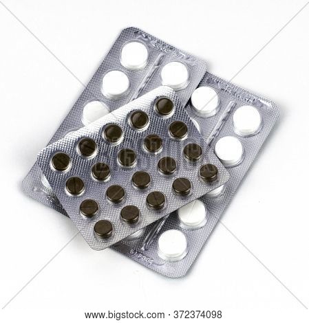 Two Packs Of White And Two Packs Of Brown Tablets In Blisters On The White Background