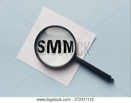 Business, Technology, Internet And Network Concept. Smm Word Acronym Throgh Magnifier On White Paper