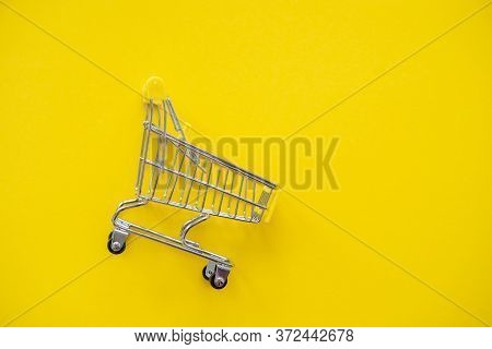 Metal Shopping Cart Close-up On A Yellow Isolated Background. Copy Space, Flat Lay, Top View