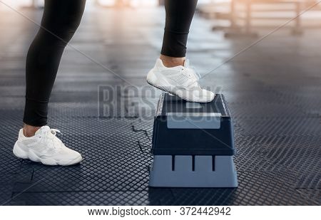 Cropped View Of Young Woman In Sports Shoes Doing Exercises With Step Platform At Gym, Close Up