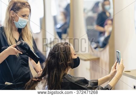 Hairdresser Drying Her Clients Hair With A Hairdryer Wearing Protective Masks In A Beauty Centre.
