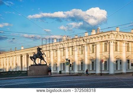 Sculptures Of Horses On The Anichkov Bridge In St. Petersburg Against The Background Of A Sunlit Bui
