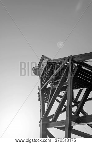 Wooden Observation Tower On A Background Of Blue Sky.black And White Photo.