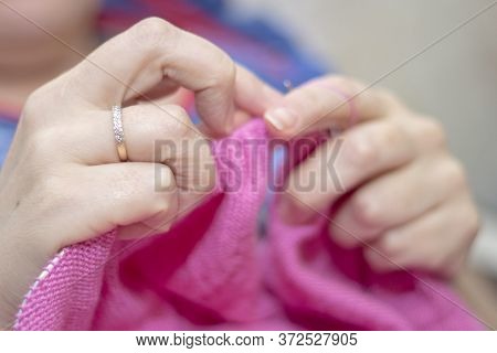 Woman Knits With Knitting Needles Light Pink Sweater From Natural Woolen Threads On Self-isolation
