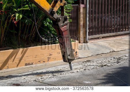 Excavator Breaking And Drilling The Concrete Road For Repairing. Large Pneumatic Hammer Mounted On T