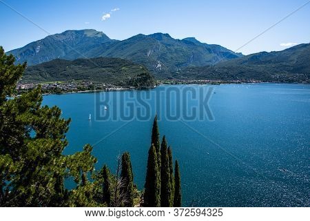 Beautiful View Of Lake Garda From The Ponale Road, With The Blue Sky, Sailing Boats, And The Green O