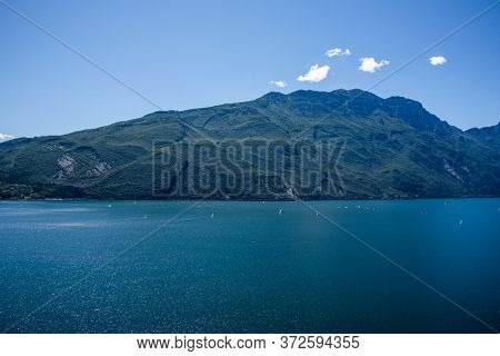 Beautiful View Of Lake Garda From The Ponale Road, With The Blue Sky, Sailing Boats, And The Green O