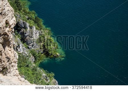 Beautiful View Of Lake Garda From The Ponale Road, With The Blue Sky, Sailing Boats, And The Green O